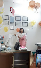 Dr. Puja Prasad in her clinic with framed medical certificates